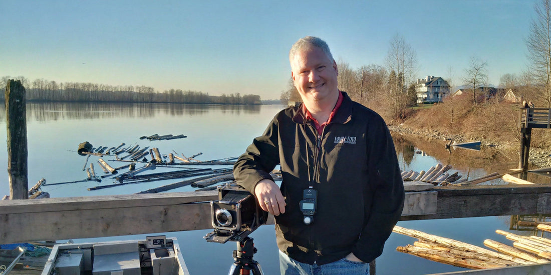 Photographer Bill Fowle standing on a dock with his Linhof camera