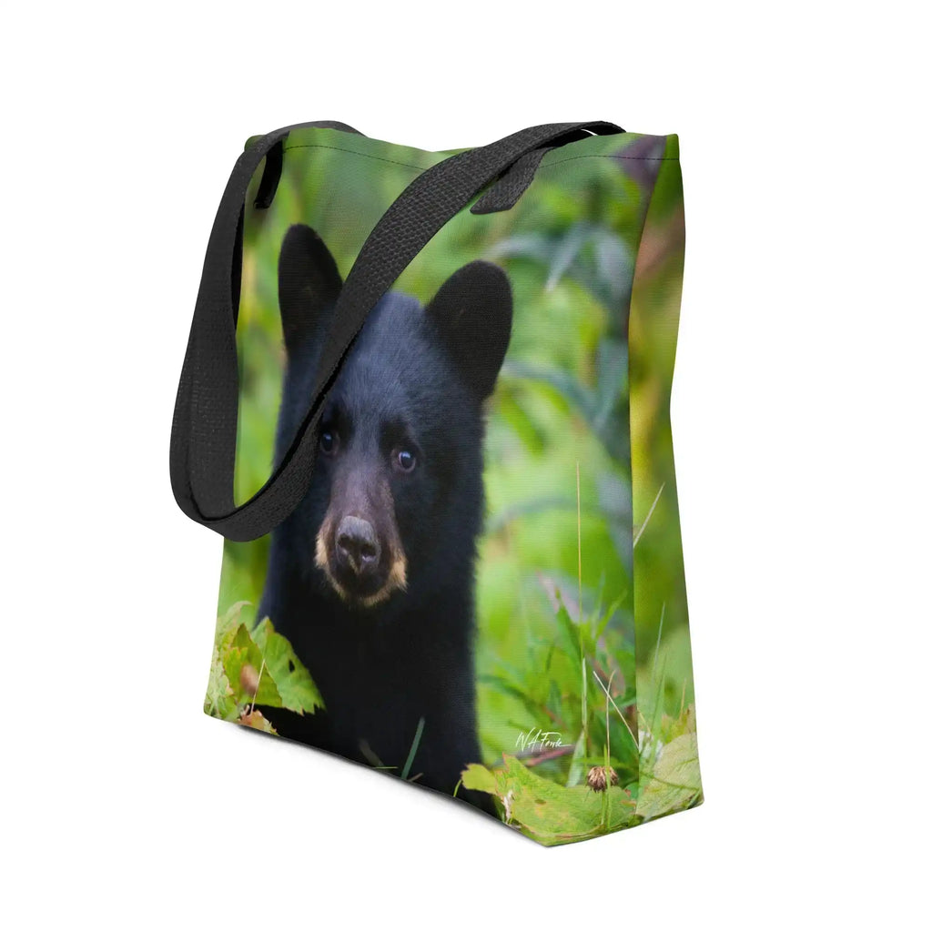 Tote bag featuring a black bear cub in green forest, nature photography accessory