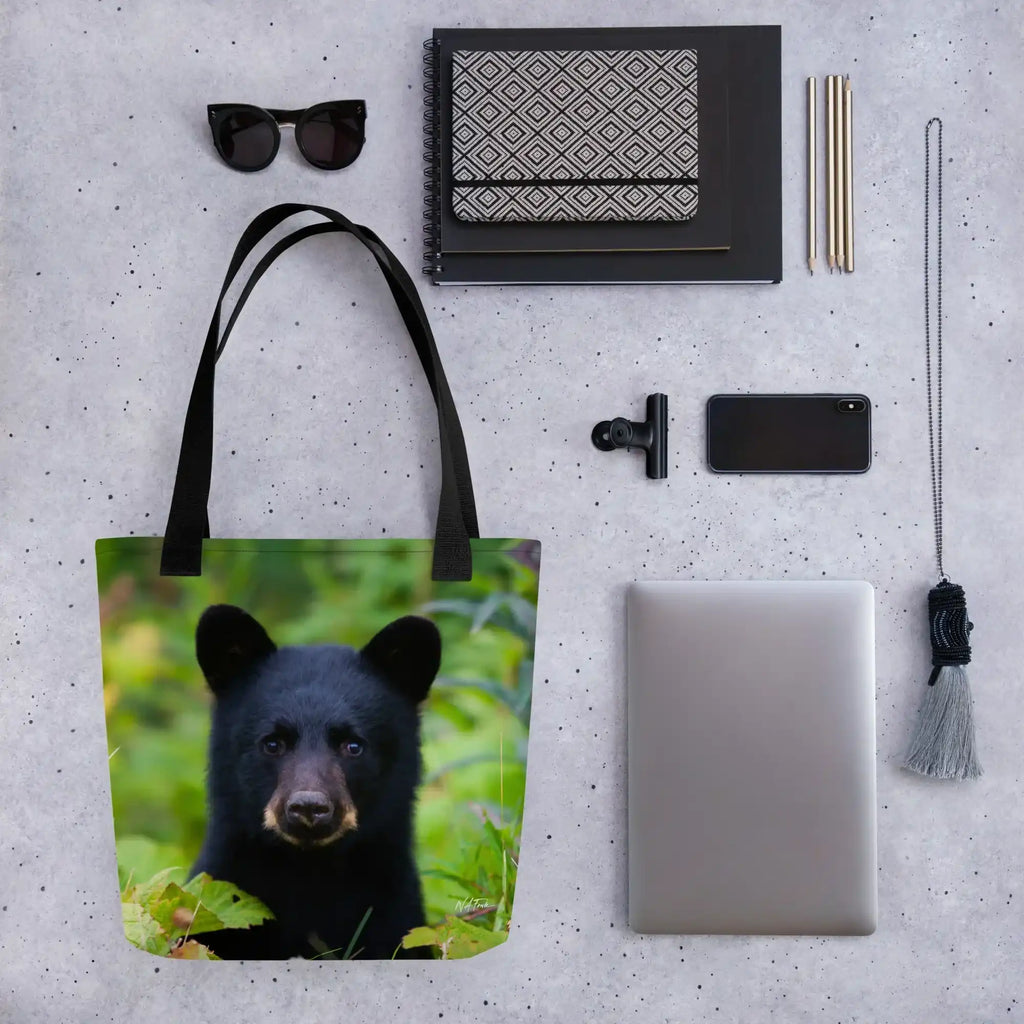 Tote bag with black bear cub photo, surrounded by modern accessories on gray background