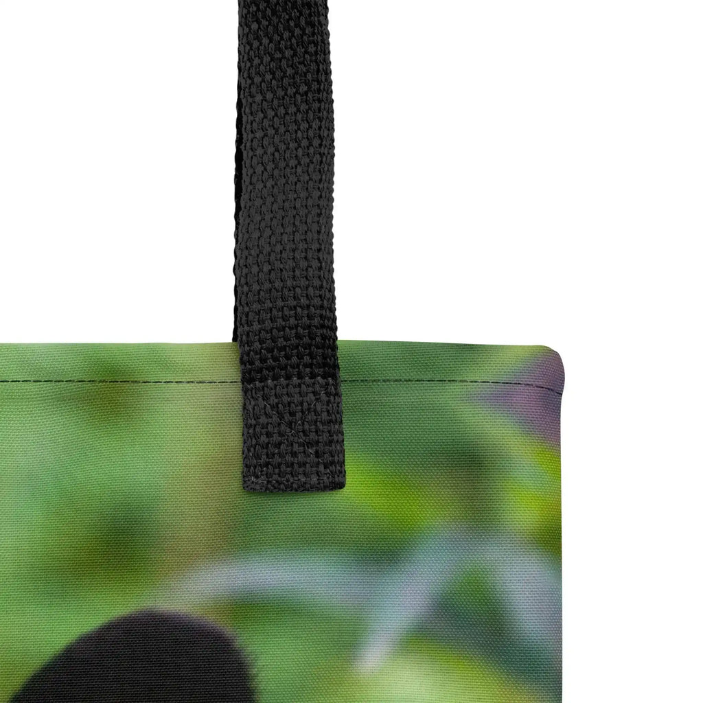 Close-up of black strap on tote bag with green nature photograph background