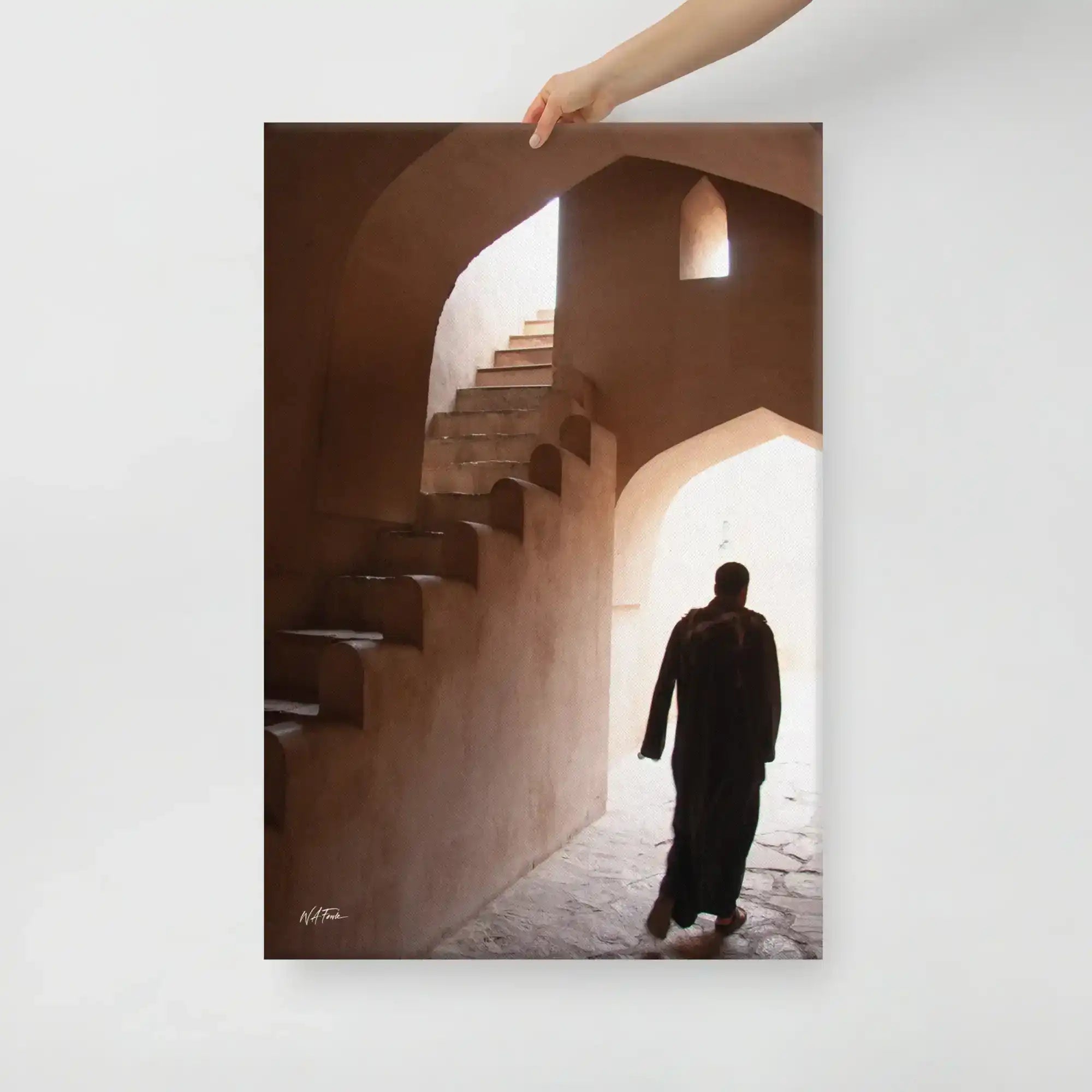 Canvas print of a person in traditional clothing walking through an arched stone corridor with stairs and natural light.