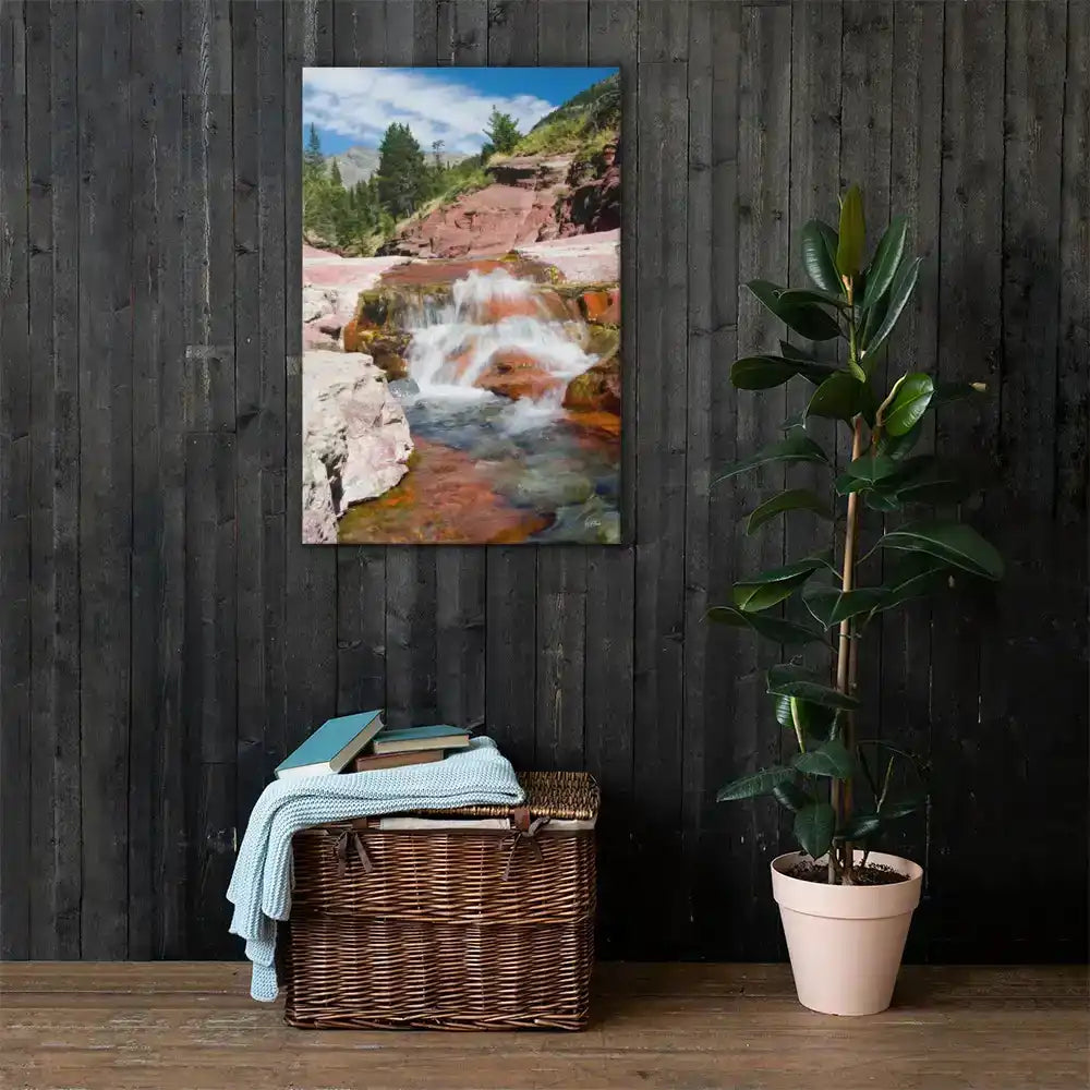 Canvas wall art of a waterfall in nature, styled on dark wood wall with plant and wicker basket.
