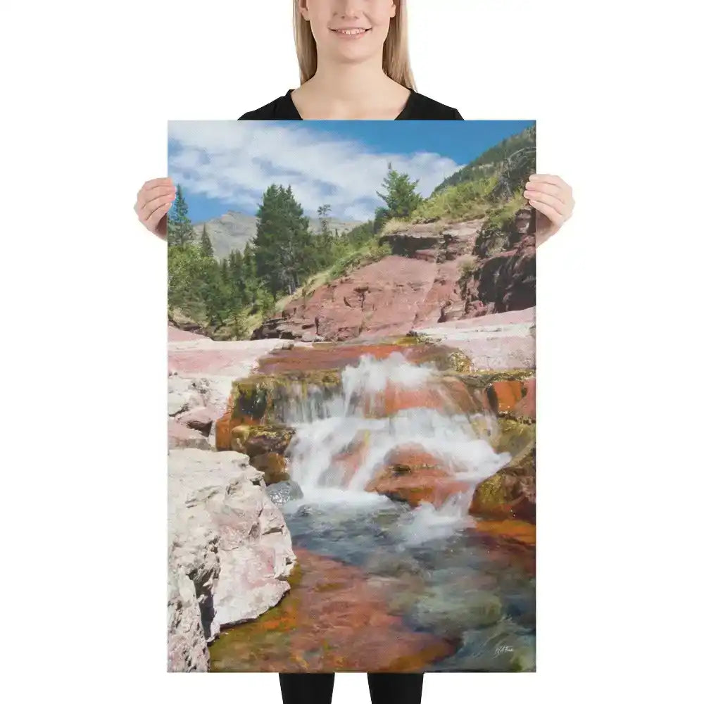 Person holding canvas print of mountain stream waterfall with red rocks and pine trees