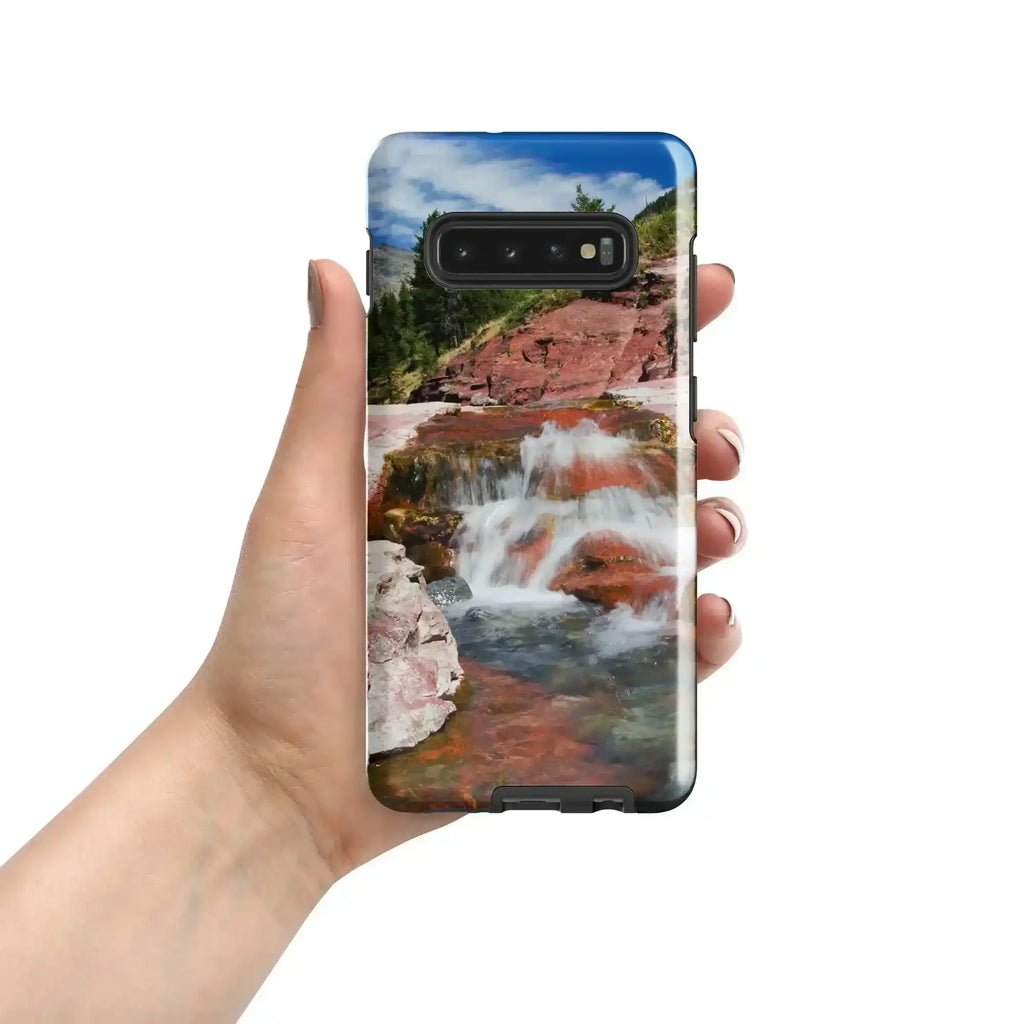 Hand holding a Samsung Galaxy S10 Plus case with a red rock waterfall landscape design