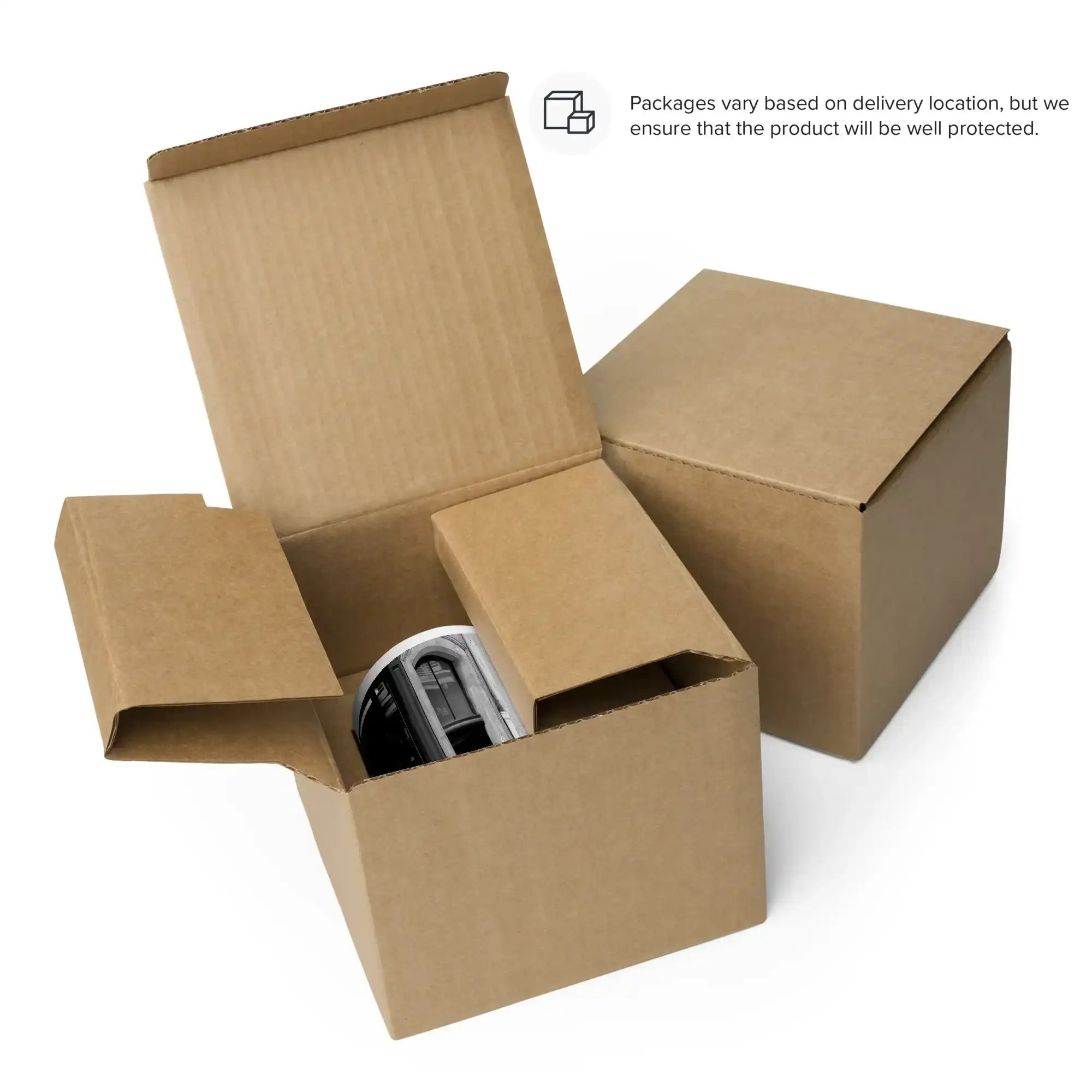 White ceramic mug partially visible inside an open cardboard shipping box, next to a closed box.