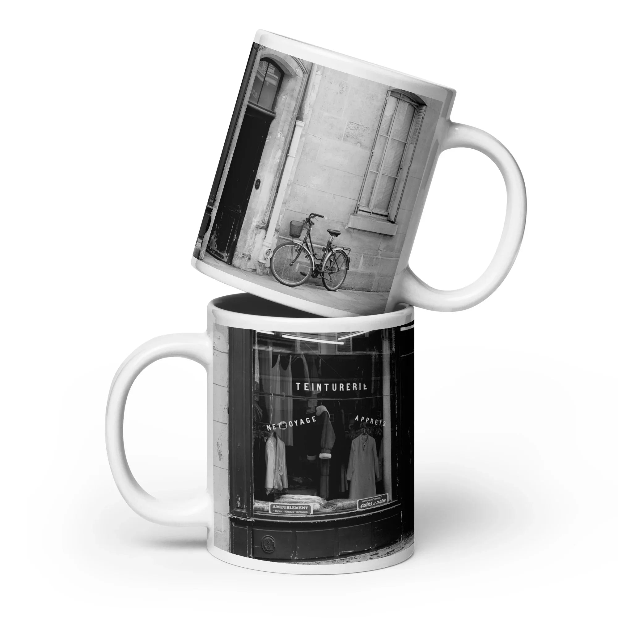 Two mugs stacked on top of each other with black and white images of a bicycle and a store front.