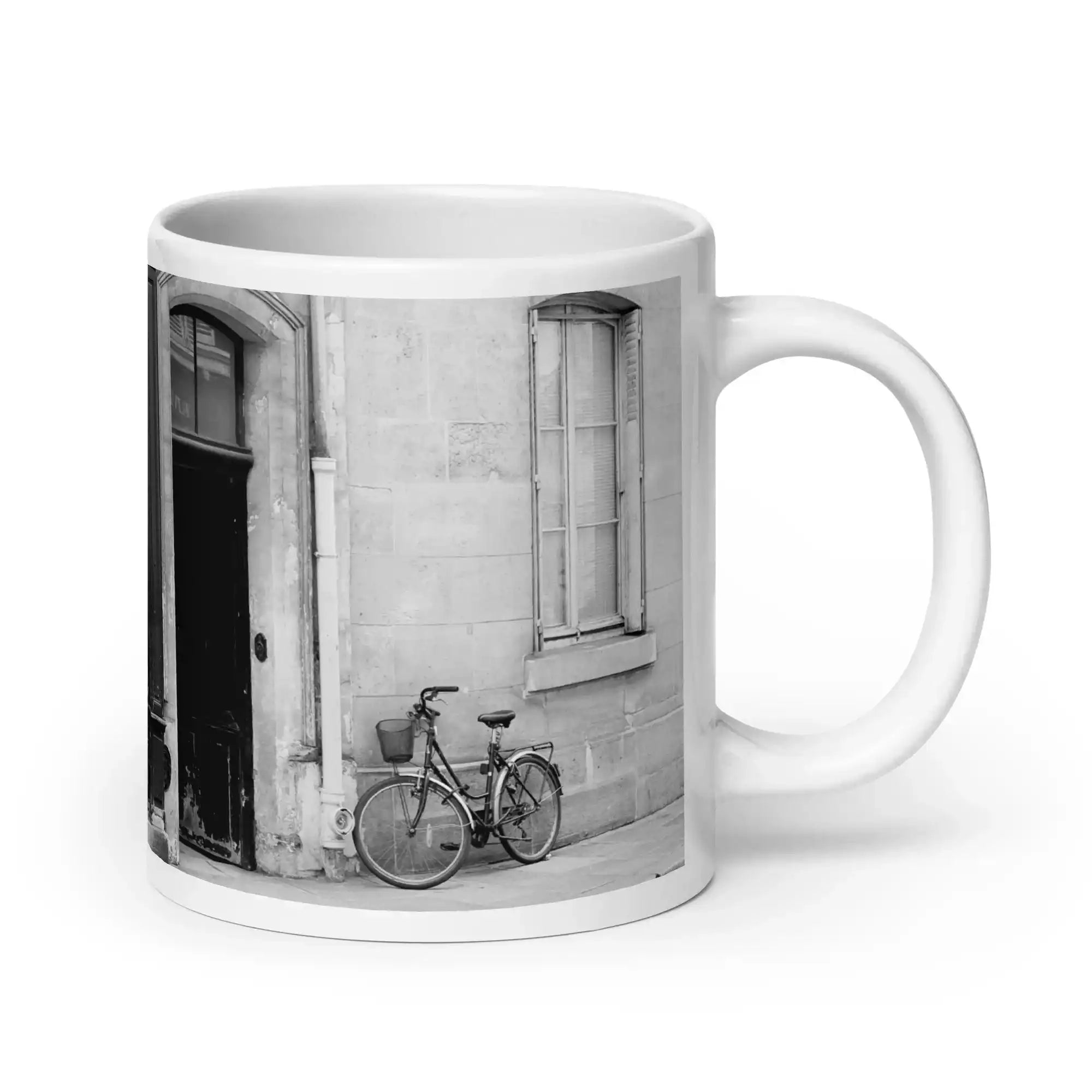 White glossy mug with black and white photo of bicycle by urban building door and window