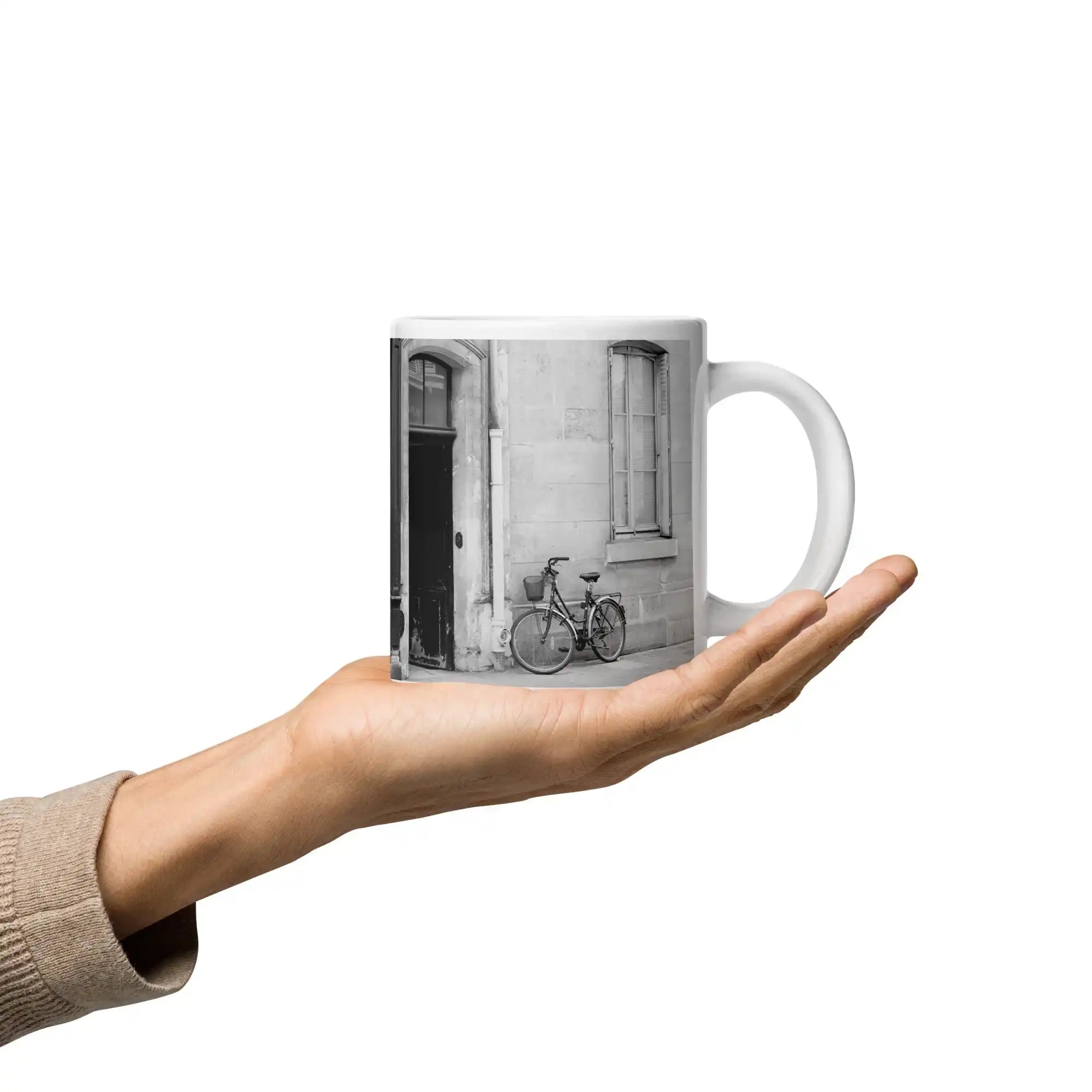 White glossy mug featuring a black and white city bicycle photo, held in a hand